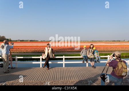 Besucher von der holländischen Keukenhof Blumengarten posieren für Urlaubsbilder vor bunte Tulpenfelder in voller Blüte. Stockfoto