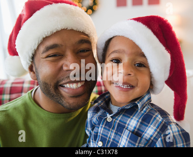 Schwarze Vater und Sohn Santa Hüte tragen Stockfoto