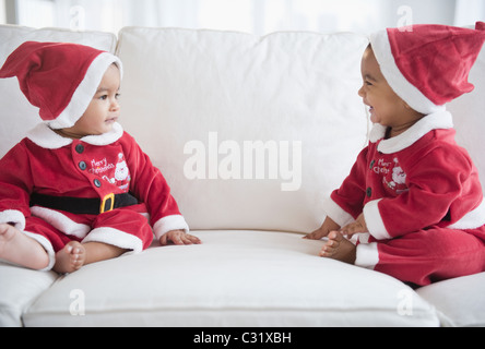 Zwillinge auf Sofa in Santa-Outfits gekleidet Stockfoto