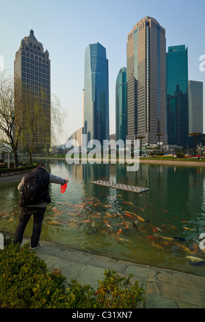 Ein Mann füttern Fische in einem Fischteich in der grün-Zentralraum Lujiazui im Stadtteil Pudong, Shanghai. Stockfoto