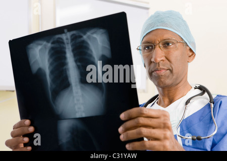 Gemischte Rassen Chirurg Blick auf Röntgenaufnahmen Stockfoto