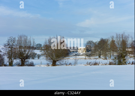 Georgian Manor House und verschneite Felder durch den River Windrush in Dorf Swinbrook, Cotswolds, Großbritannien Stockfoto