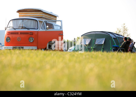 Paar sitzt mit Zelt und Volkswagen W Wohnmobil in einem Feld in das Morgenlicht camping in East Sussex Stockfoto