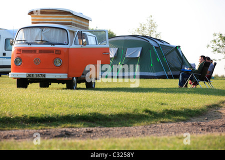 Paar sitzt mit Zelt und Volkswagen W Wohnmobil in einem Feld in das Morgenlicht camping in East Sussex Stockfoto