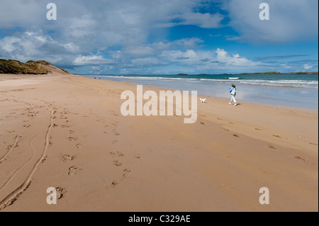 Eine Frau geht ihren Hund am Strand von den weißen Felsen in der Nähe von Portrush in Nordirland Stockfoto
