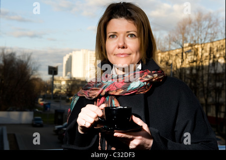 lächelnde Frau in einer Straße im Herbst Kleidung mit einer Tasse Kaffee Stockfoto