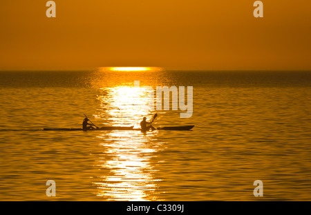 Zwei Kajakfahrer Silhouette gegen orange sunset Himmel über Golf von Mexiko aus Venice Beach Florida Stockfoto