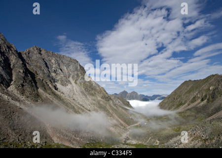 Tal mit Nebel im Sajan-Gebirge vor blauem Himmel mit Wolken. Ost-Sajan-Gebirge. Sibirien. Russland / Stockfoto