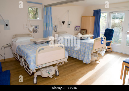 Zwei Betten in einem Hospiz mit der Sonne in und große Fenster Stockfoto