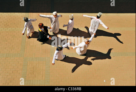 Oman, Maskat, Draufsicht von Schuljungen mit Armen heraus stehen und tanzen auf dem Boden an einem sonnigen Tag Stockfoto