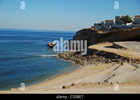 Oman, Wadi Shab, kurvenreiche Straße mit Häusern auf felsigen Klippen vom Blau des Meeres Stockfoto