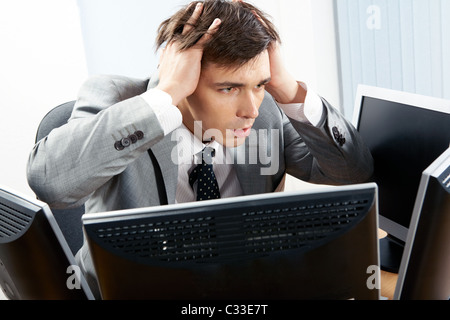 Porträt von frustrierten Arbeitgeber vor Computer mit den Händen am Kopf sitzen Stockfoto
