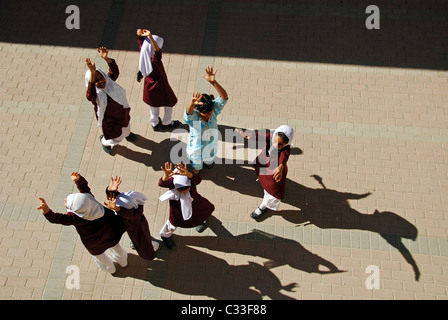 Oman, Maskat, Draufsicht der Schulmädchen spielen mit Armen auf dem Boden an einem sonnigen Tag Stockfoto