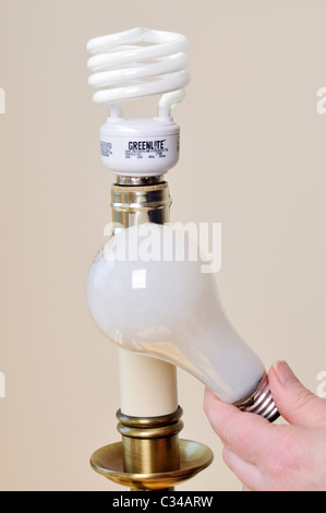 Erwachsenen Hand Lampenwechsel Licht einer Lampe aus einer Glühlampe auf eine weitere energiesparende Kompaktleuchtstofflampe. USA Stockfoto