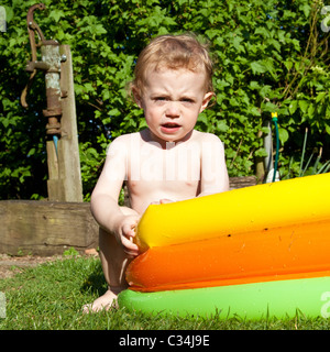 Junge (2 Jahre alt) spielen in einem Planschbecken, Hampshire, England. Stockfoto