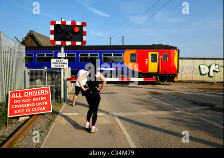 Jogger am ein Bahnübergang warten, während eine lokale s-Bahn Beeston Nottingham England uk verläuft Stockfoto