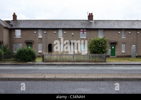 Ein besetztes Haus, das die Flagge von St. George zeigt, zwischen verschlossenen, heruntergekommenen Häusern, Grangetown, Middlesbrough, England, Großbritannien. Januar 2011. Stockfoto