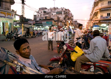 Ein Männchen Cyclo-Fahrer wartet auf die Passagiere auf einem Markt auf einer belebten Straße in Phnom Penh, Kambodscha. Stockfoto