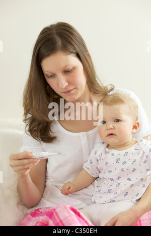 Schreiendes Baby, die ihre Körpertemperatur mit digital-Thermometer von der Mutter genommen Stockfoto