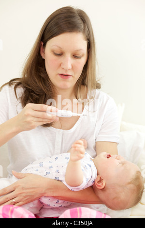 Schreiendes Baby, die ihre Körpertemperatur mit digital-Thermometer von der Mutter genommen Stockfoto