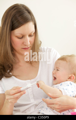 Schreiendes Baby, die ihre Körpertemperatur mit digital-Thermometer von der Mutter genommen Stockfoto