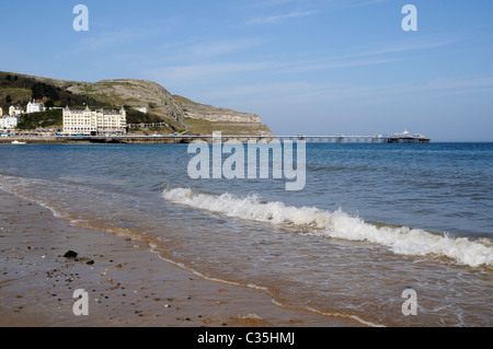 Wellen brechen sanft am Strand von Llandudno mit dem Pier im Hintergrund Stockfoto