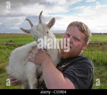 Landwirt Holding Ziegenbock auf seiner Farm in Island Stockfoto