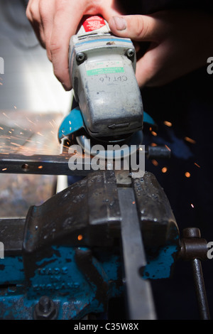 Eine Person benutzt, einem Winkelschleifer auf Metall, statt in einen Schraubstock Stockfoto