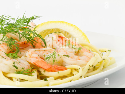 Dill Zweige und Zitronenscheibe bieten Beilagen für Garnelen Scampi auf Spaghetti Nudeln auf weißem Teller serviert. Stockfoto