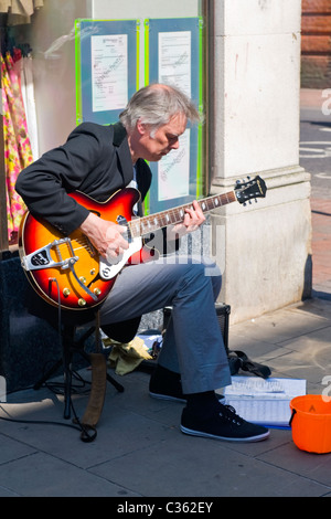 Winchester City, Mann mittleren Alters grau oder grauen Haaren Glatzenbildung spielt e-Gitarre Straßenmusik in der High Street außerhalb & S M Stockfoto