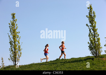 Zwei weibliche Hobby-Läufer in einem öffentlichen Park. Joggen bergauf. Stockfoto