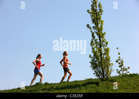 Zwei weibliche Hobby-Läufer in einem öffentlichen Park. Joggen bergauf. Stockfoto