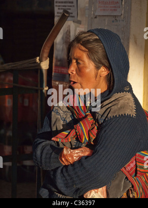 Eine einheimische Maya-Frau ist von der Seite gesehen, in den späten Abend warmes Licht, während sie entlang einer Straße in traditionell gekleidet geht. Stockfoto