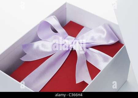 Nahaufnahme von roten Geschenkbox mit Schleife Band in offenen weißen Feld auf isolierte Hintergrund Stockfoto