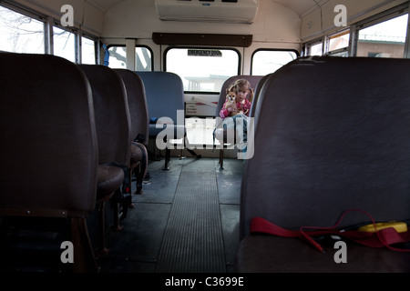 Mädchen hält einen Hund auf einen Schulbus Stockfoto