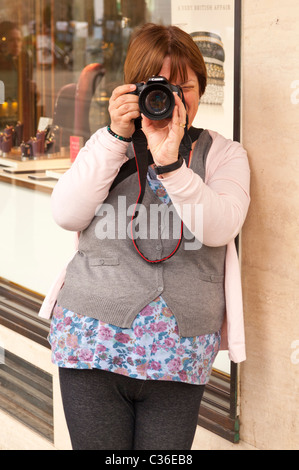 Eine Fotografin, die eine Aufnahme mit ihrer Canon digitale SLR-Kamera im Vereinigten Königreich Stockfoto