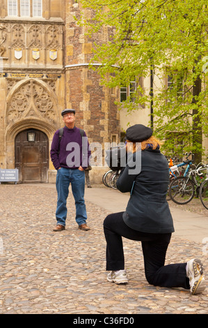 Eine Frau nimmt ein Foto eines Mannes gegenüber Trinity College in Cambridge, Cambridgeshire, England, Großbritannien, Uk Stockfoto