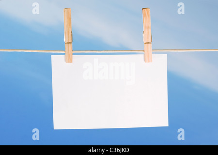 leeres Blatt Papier und Wäscheklammer auf blauen Himmelshintergrund Stockfoto
