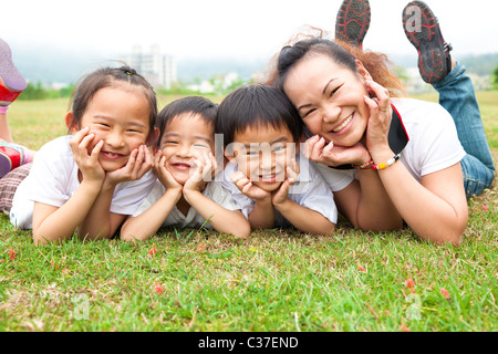 Muttertag. asiatische Mutter und ihre Kinder auf der grünen Wiese Stockfoto