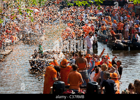 Königstag, des Königs Geburtstag (Königinnentag Königinnentag) in Amsterdam Canal Parade Boote Menschen feiern schießen orangefarbene Konfetti. Stockfoto