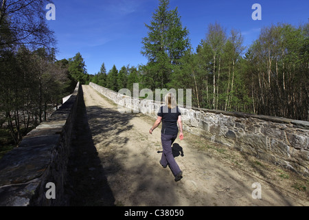 Walker über neu renovierte (2011) alte Invercauld Brücke über den Fluss Dee in der Nähe von Braemar in Aberdeenshire, Schottland, Vereinigtes Königreich Stockfoto