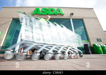 Ein Mitarbeiter sammelt Wagen außerhalb einer ASDA Stores. Stockfoto