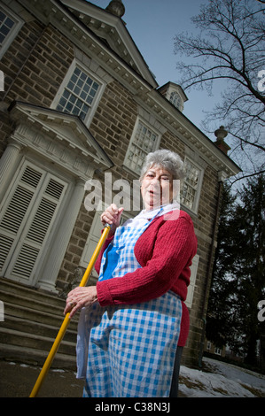 Ältere Frau fegt äußeren historischen Altbau, Philadelphia, USA Stockfoto