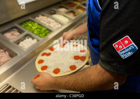 Ein Domino Pizza Mitarbeiter vorbereiten eine frische Pizza Kochen Ofen betriebsbereit. Stockfoto