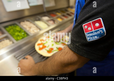 Ein Domino Pizza Mitarbeiter vorbereiten eine frische Pizza Kochen Ofen betriebsbereit. Stockfoto