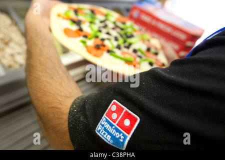 Ein Domino Pizza Mitarbeiter vorbereiten eine frische Pizza Kochen Ofen betriebsbereit. Stockfoto