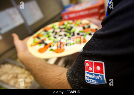 Ein Domino Pizza Mitarbeiter vorbereiten eine frische Pizza Kochen Ofen betriebsbereit. Stockfoto