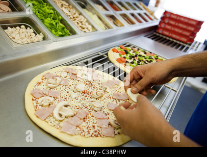 Ein Domino Pizza Mitarbeiter vorbereiten eine frische Pizza Kochen Ofen betriebsbereit. Stockfoto