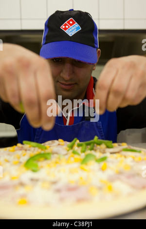 Ein Domino Pizza Mitarbeiter vorbereiten eine frische Pizza Kochen Ofen betriebsbereit. Stockfoto