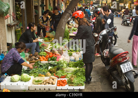 Horizontale Ansicht des unorganisierten Chaos auf einer Straße in der Altstadt in Hanoi mit Obst und Gemüse Ständen entlang der Bürgersteige. Stockfoto